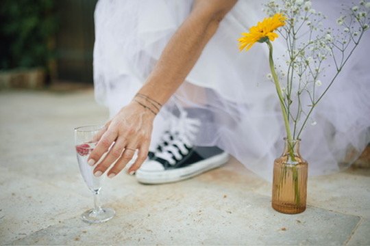 Les baskets sous la robe, un verre posé — la mariée reprend son souffle.