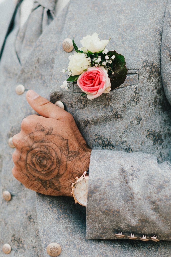 Détail du costume du marié : main tatouée, montre et boutonnière